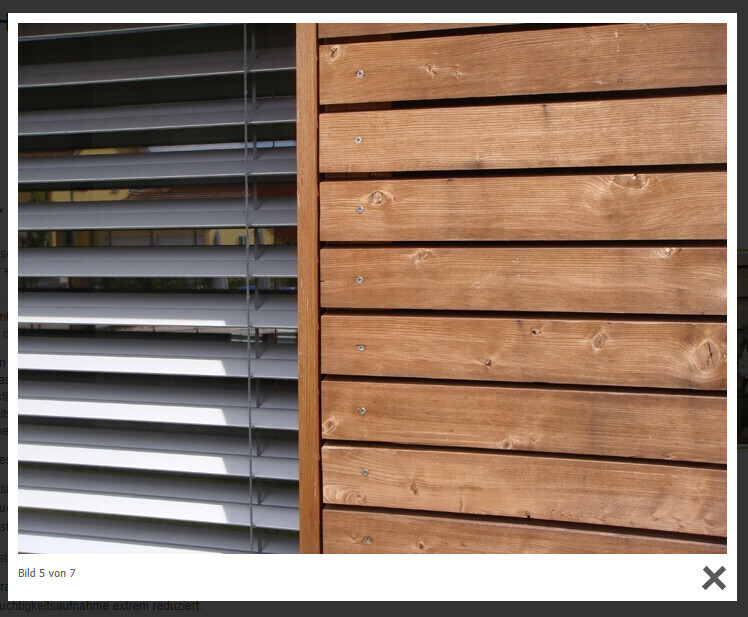 Aussenfassade: rechte Holzplanken, linkes Fenster mit Jalousien