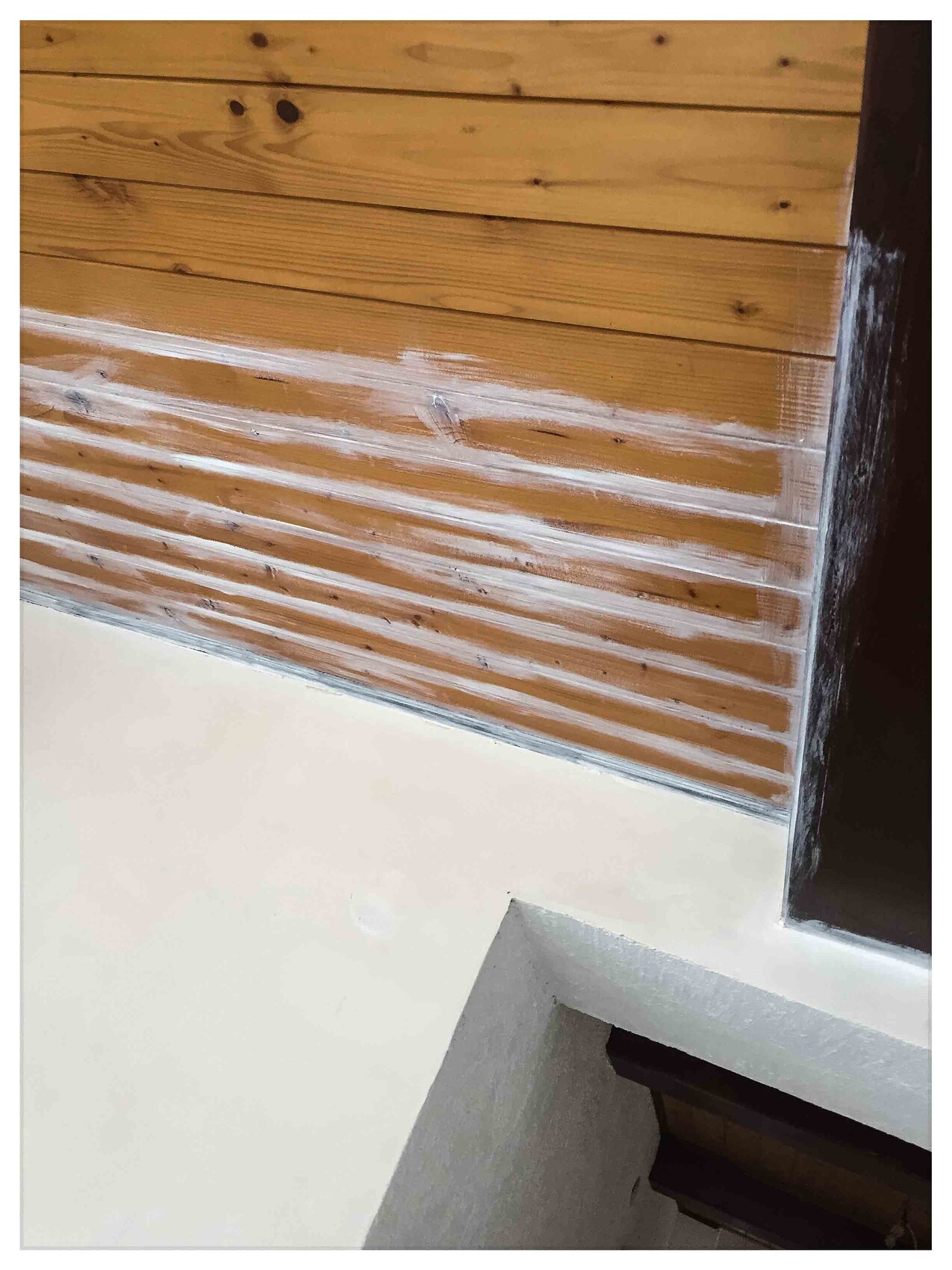 Innenwand aus Holzpaneelen mit weißem Sockelbereich und sichtbaren Fugen