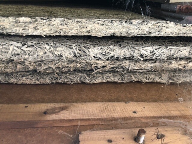 OSB-Platten stapeln sich auf Holzboden, vorne Schraubenkopf sichtbar.