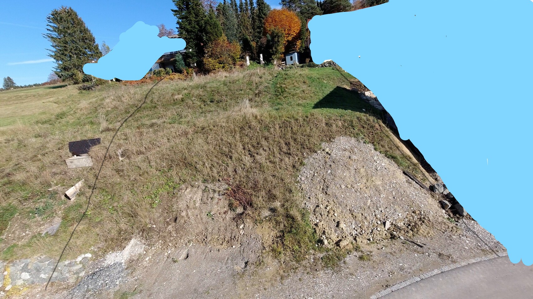 Hügelige Wiese mit Herbstbäumen, kleine weiße Hütte im Hintergrund, felsiger Abhang im Vordergrund