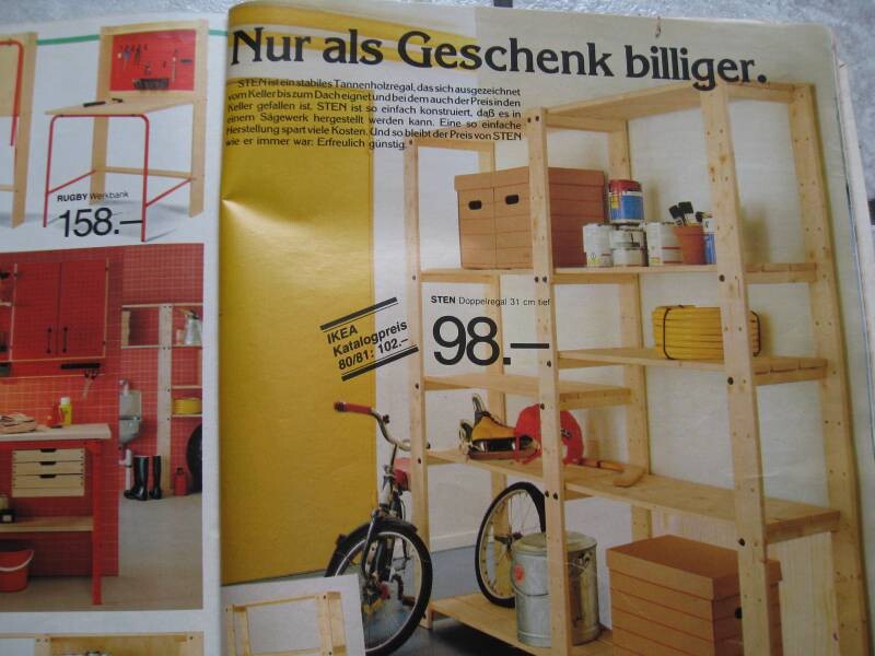Holzregal-Display im Möbelhaus, Fahrrad davor, Preisschild 98,- vor gelber Wand.