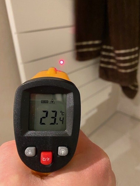 Infrarot-Thermometer zeigt 23.4°C; roter Laserpunkt markiert Messpunkt, Hand hält das Gerät.
