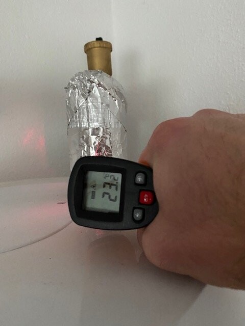 Nahaufnahme eines aluminiumfolie-umwickelten Behälters und eines Hand-Thermometers.