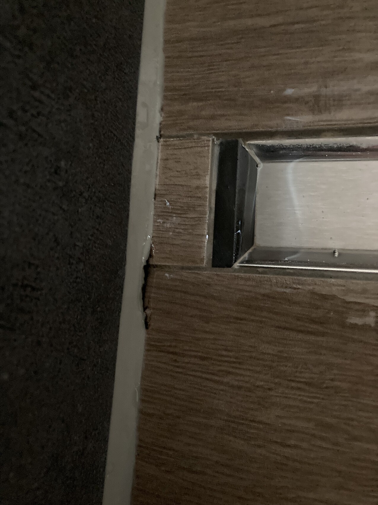 Nahaufnahme eines Holztürrahmens mit silberner Metallplatte am Rand