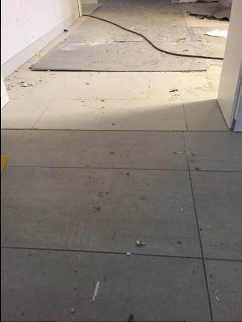 Renovierungsbereich: schmutziger Fliesenboden, Kabel, Staub und Schutt.