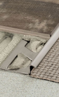 Nahaufnahme eines Bodenprofil-Kantenübergangs zwischen Teppich und Fliesen aus Metall.