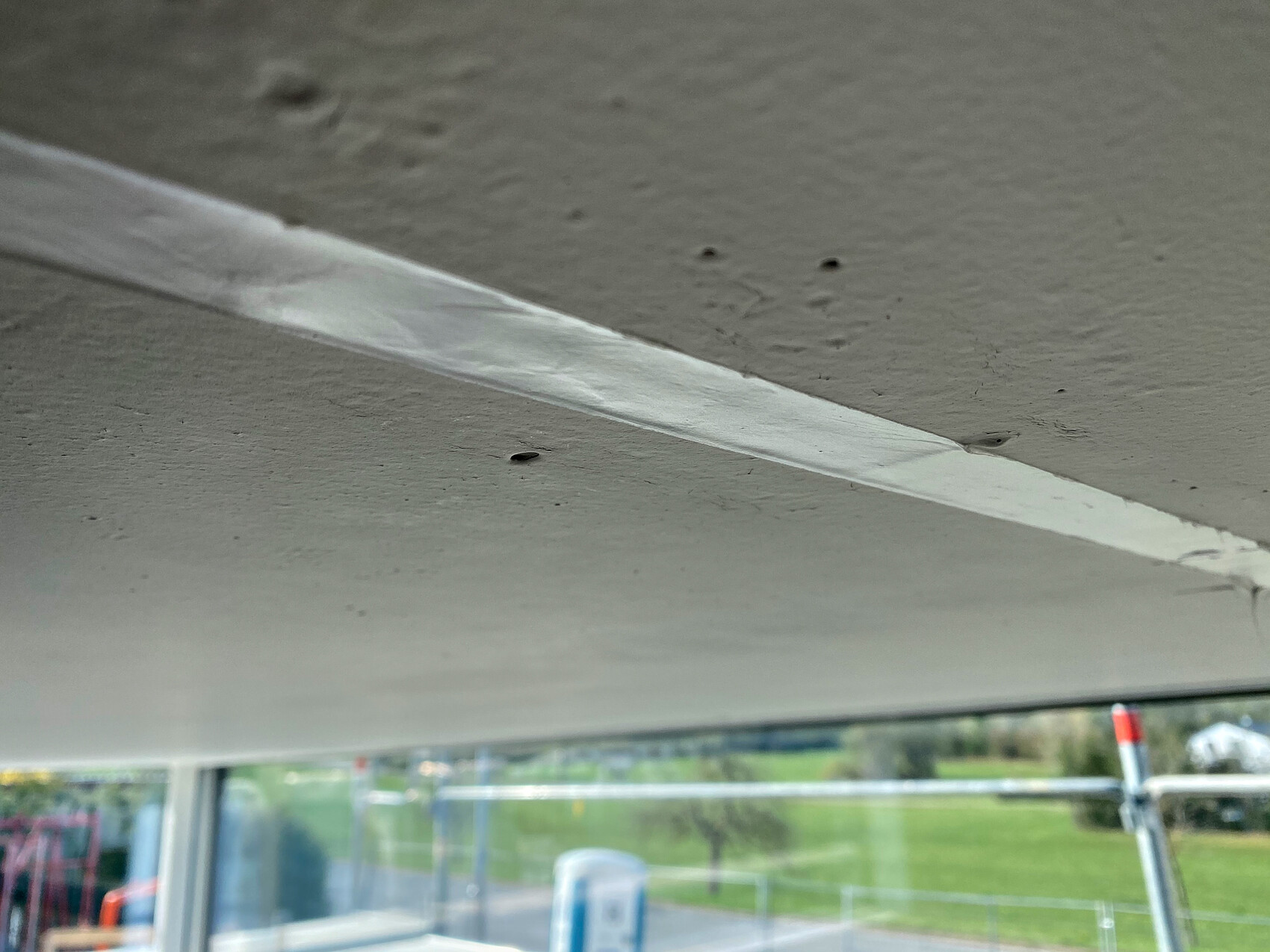 Innenansicht der Busdecke mit weißem Klebebandstreifen; Fenster unten zeigt Außenlandschaft.