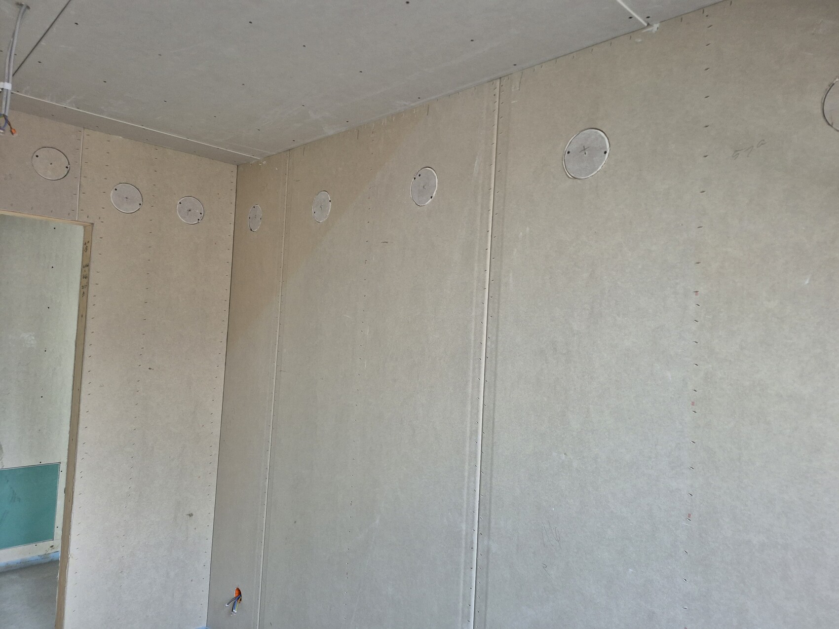 Innenraum eines Neubauhauses mit Gipskartonwänden und runden Kabeldurchführungen