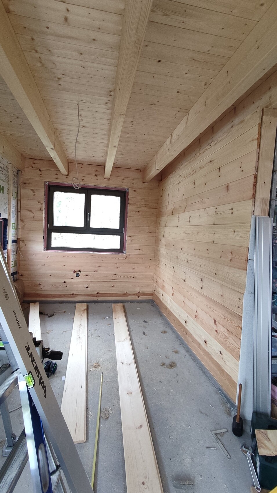 Innenraum im Bau mit Holzwänden, Holzbalkendecke, Fenster und Bauwerkzeugen