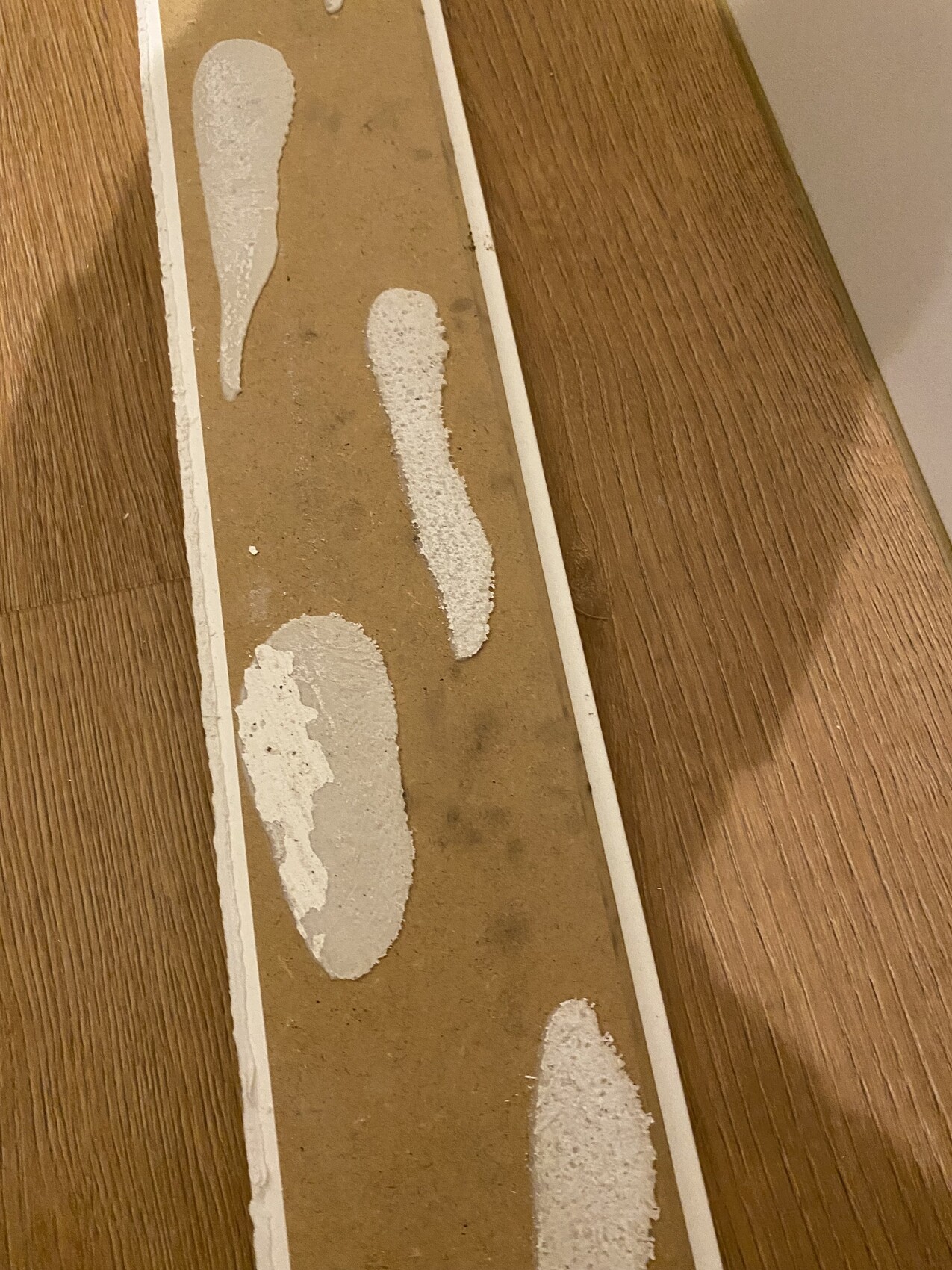 Langer brauner Streifen mit weißen fußabdruckähnlichen Flecken liegt auf einem Holztisch.