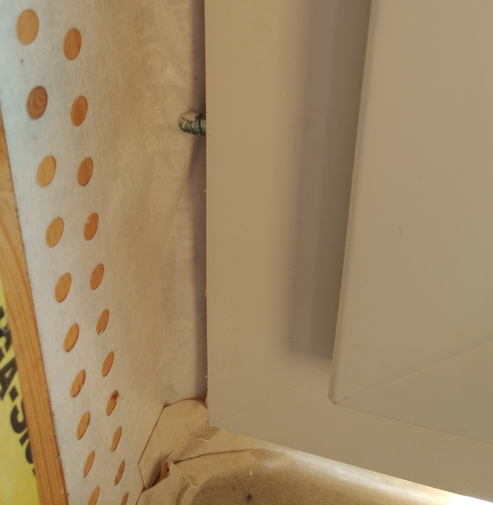 Nahaufnahme eines weißen Rahmens neben Lochplatte Pegboard im Innenausbau.