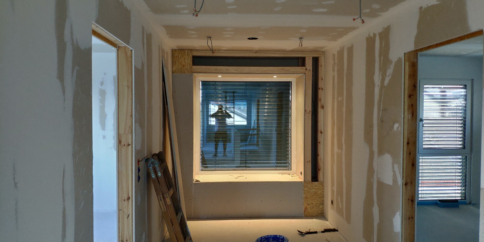 Innenraum im Bauzustand mit Trockenbauwänden, Fenster in der Mitte, Leiter.