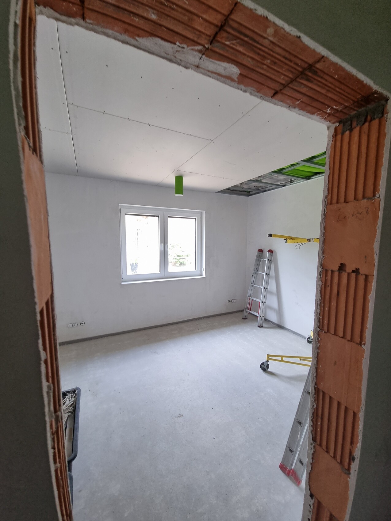 Unfertiges Innenraumzimmer im Ausbau mit Leiter, offener Decke und Baumaterialien