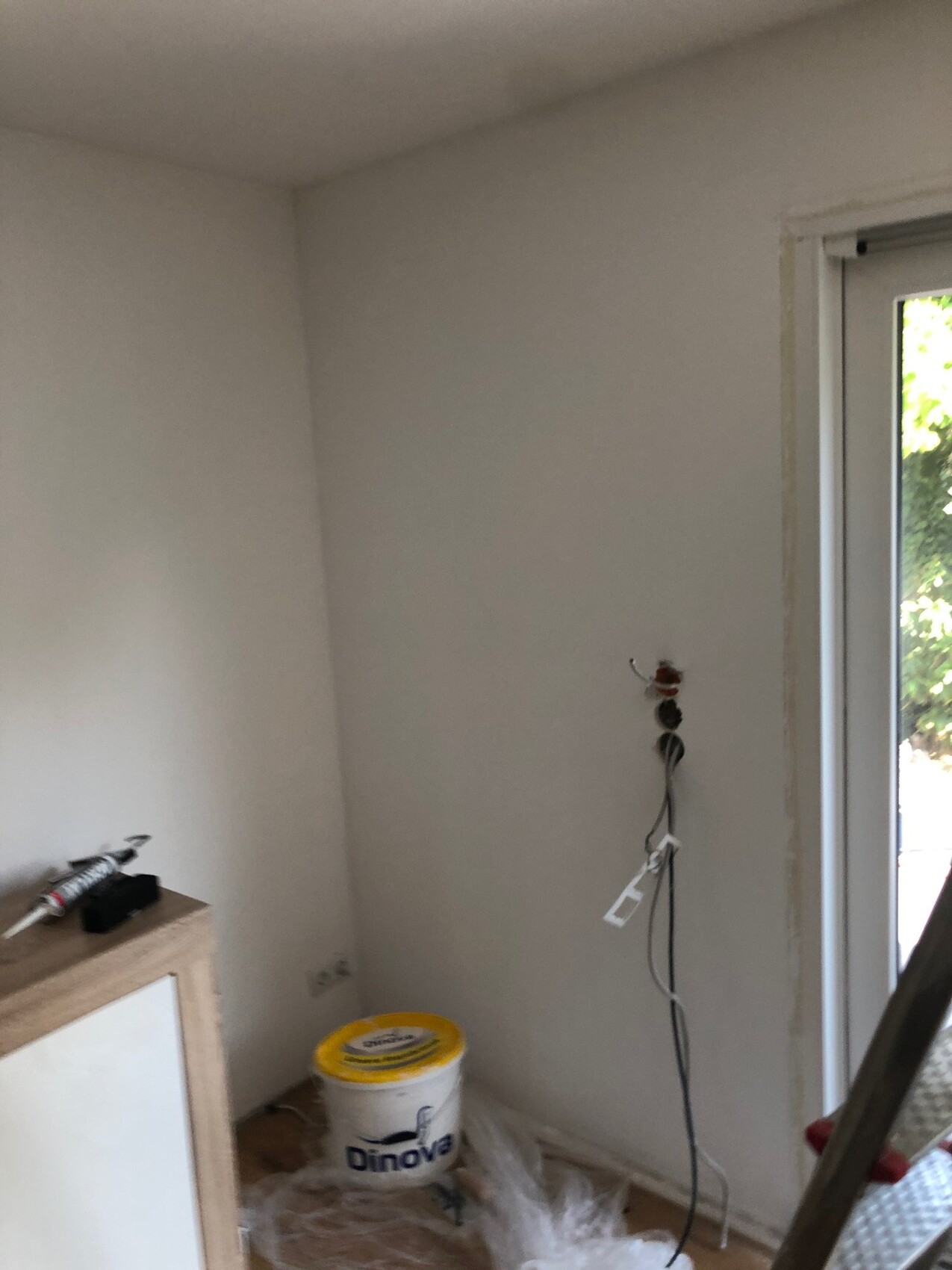 Renovierter Innenraum: Kabel, Eimer, Abdeckfolie und Tür nach draußen.