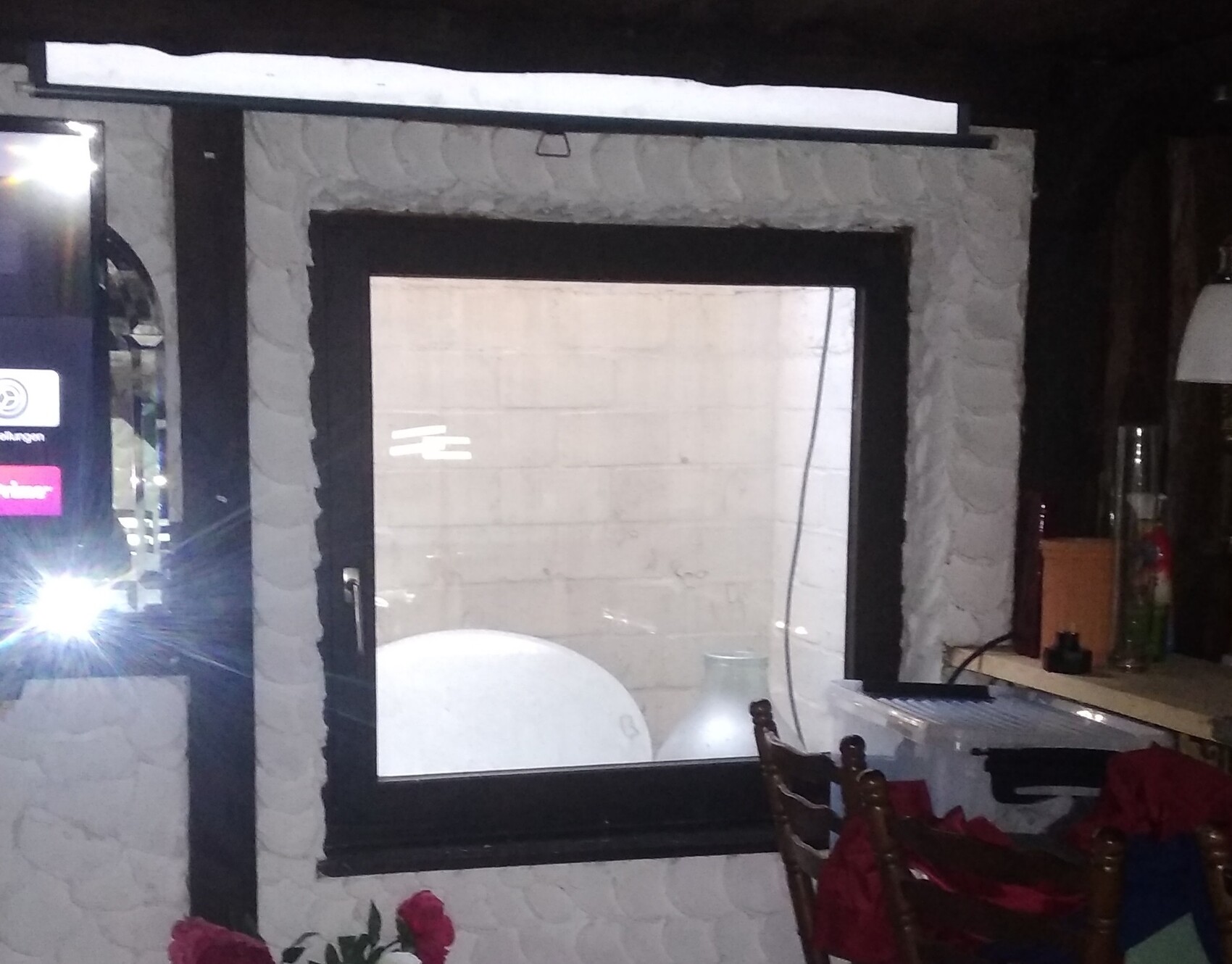 Fenster in dunkler Steinwand, Innenausbau mit heller Einrichtung und Möbeln