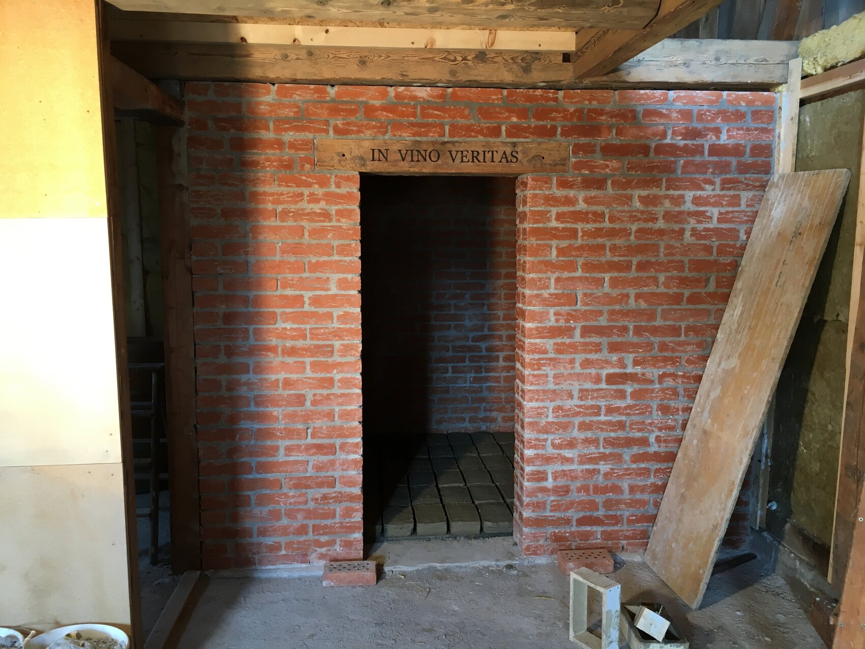 Rote Backsteinwand mit Türbogen im Innenausbau eines unfertigen Weinkellers