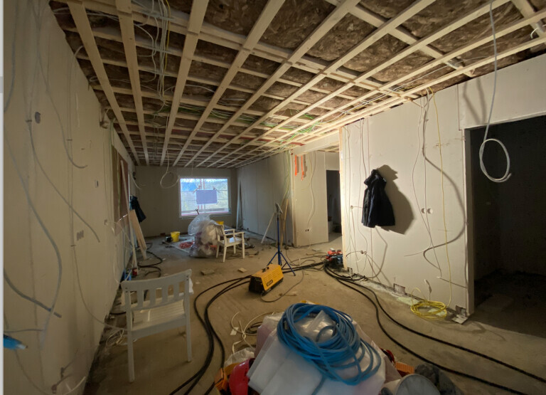 Renovierungsraum: offene Decke, Kabel, Werkzeuge, Materialien und Möbel verteilt.