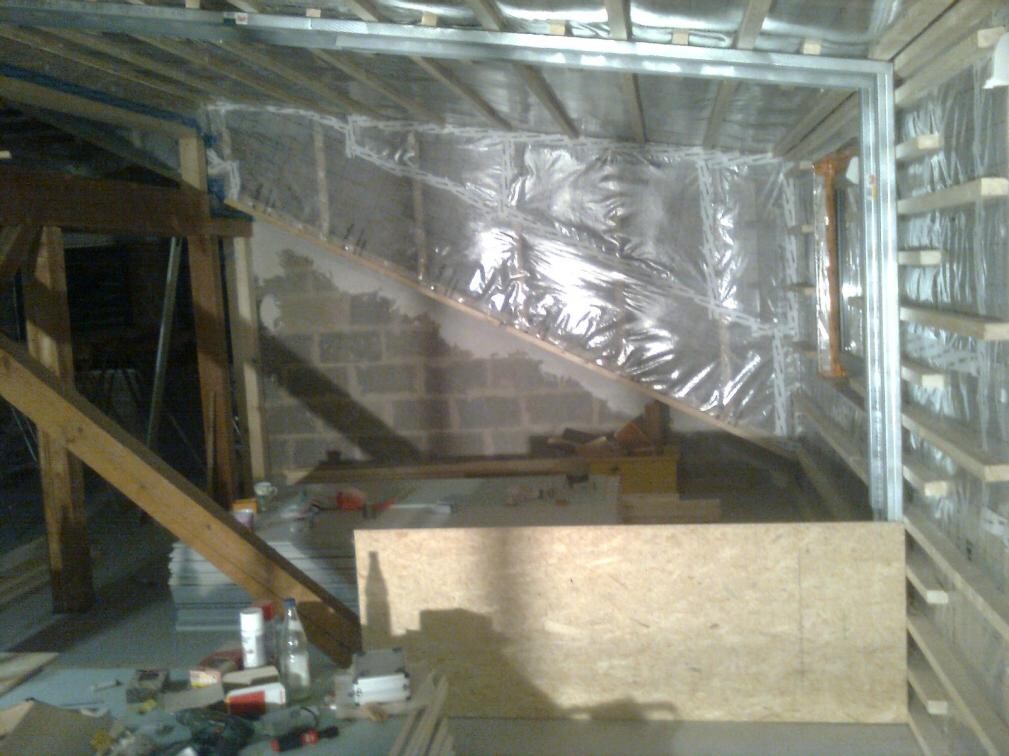 Innenbereich eines Rohbaus mit Holzkonstruktion, Treppe und Folienverkleidung