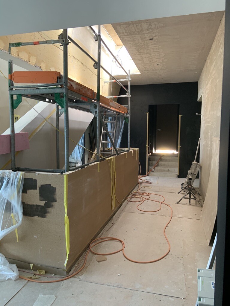 Innenraum einer Baustelle mit Gerüst, Baumaterialien, Kabeln und Plastikfolien.