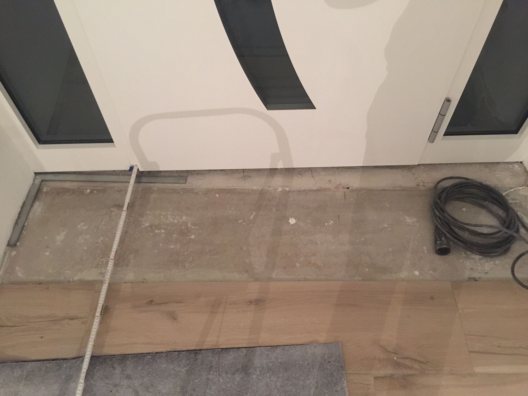 Innenausbau: Türfront, unvollständiger Boden, Messband und Kabelrolle auf der Baustelle