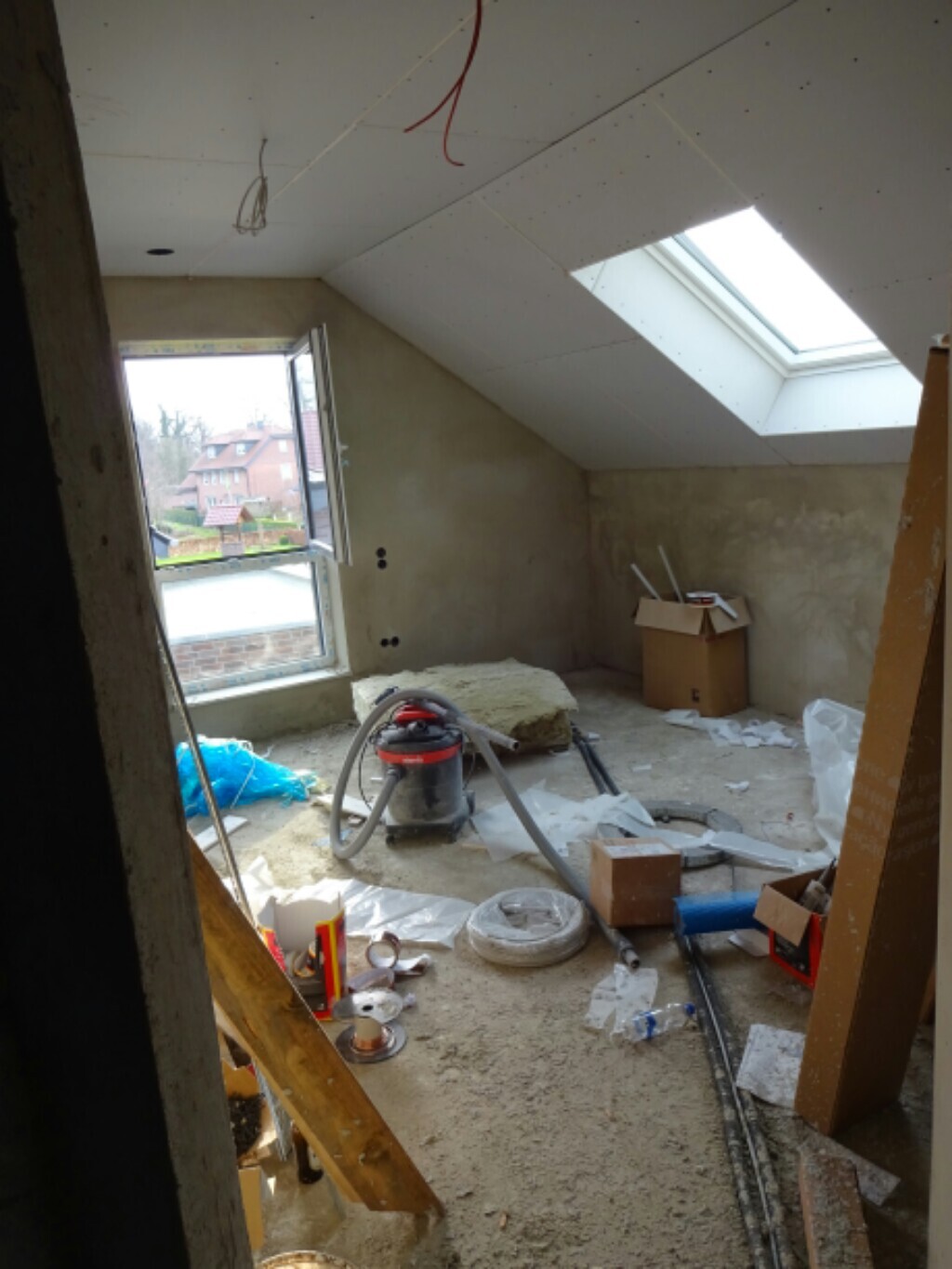 Unfertiger Dachboden/Attikaraum mit Dachfenster, Werkzeugen und Baumaterialien