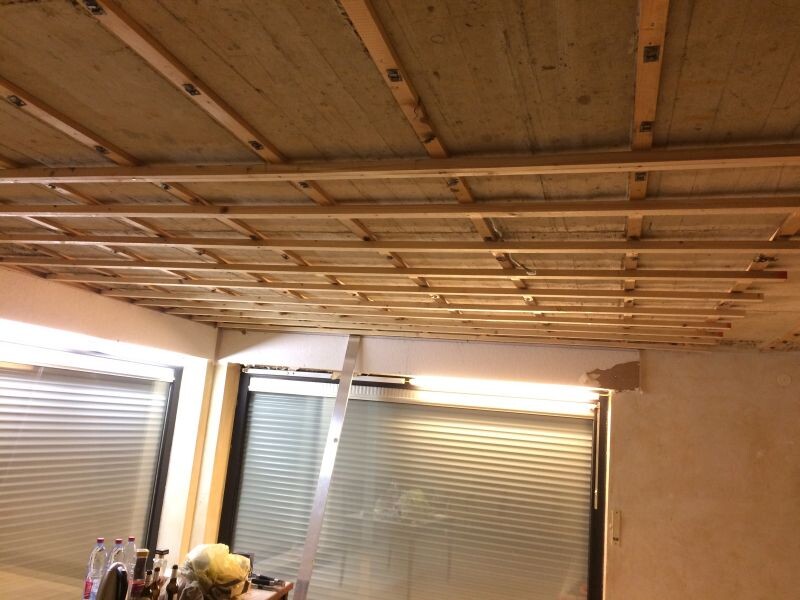 Raumdecke mit Holzunterkonstruktion während Renovierung und Fensterfronten sichtbar