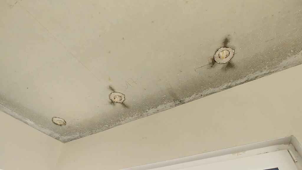 Weiße Decke mit drei runden Aussparungen/Bohrlöchern, Renovierungsarbeiten sichtbar