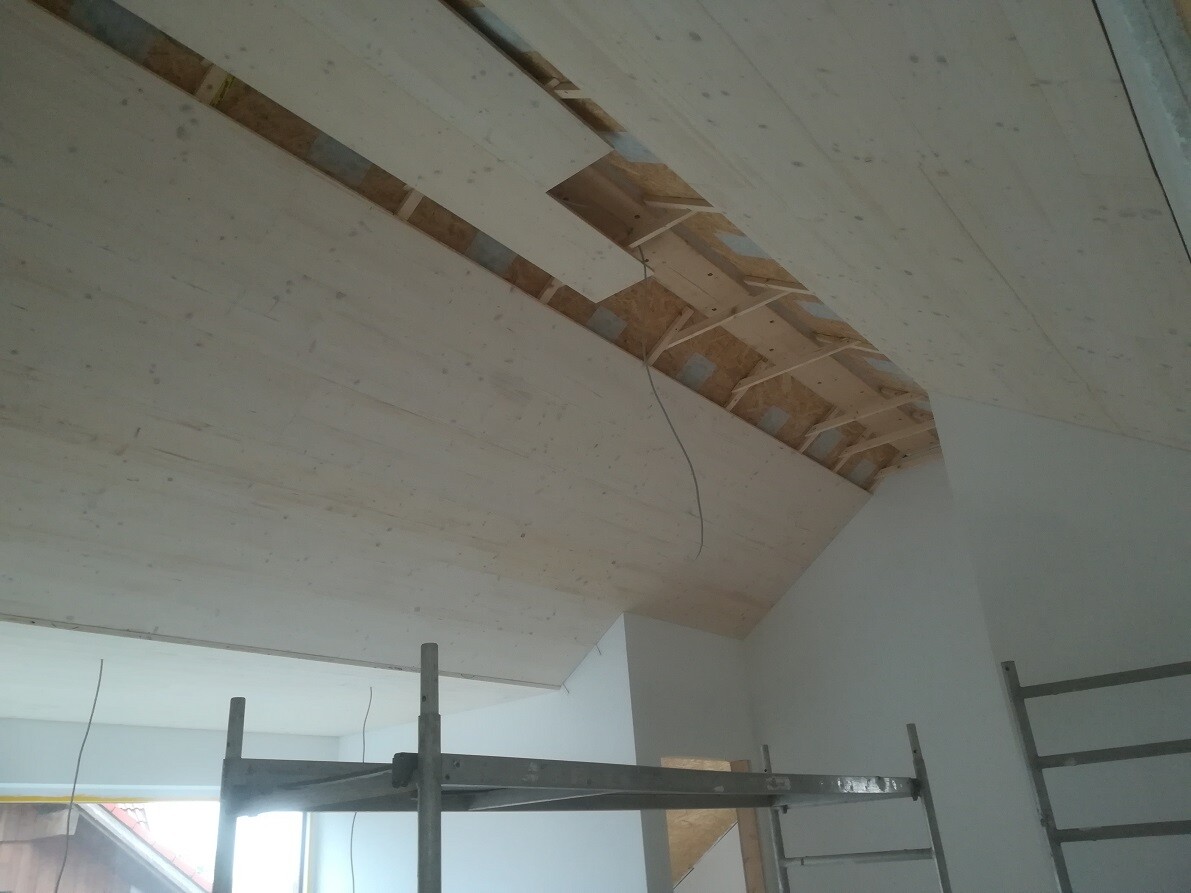 Sicht auf unfertige Deckenstruktur: Holzplatten, OSB, Kabel und Gerüst.