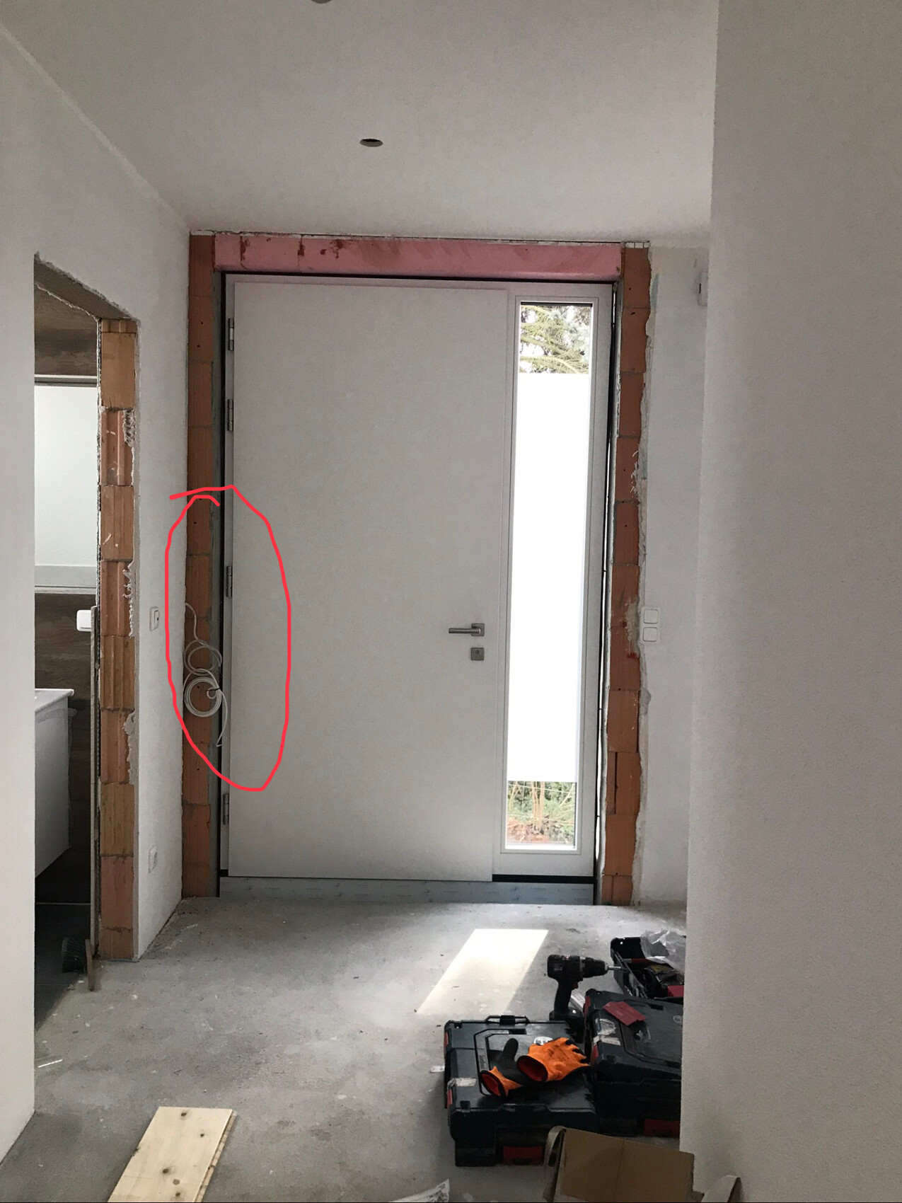 Renovierungsbereich: Innentür installiert, Kabel an der Wand, Werkzeug am Boden.