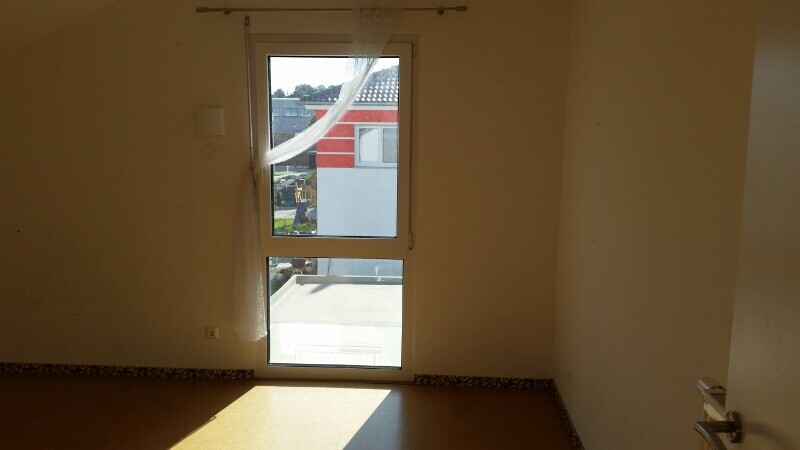 Leerer Innenraum mit Fensterfront und Vorhang, Sonnenlicht fällt auf den Boden