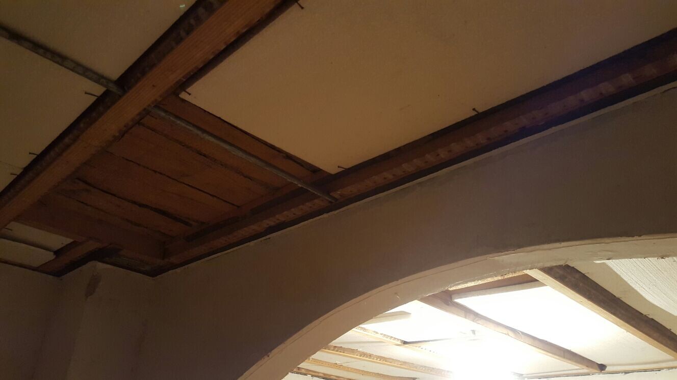 Innenansicht eines Renovierungsraums mit offenen Holzbalkendecken und Bogenstrukturen