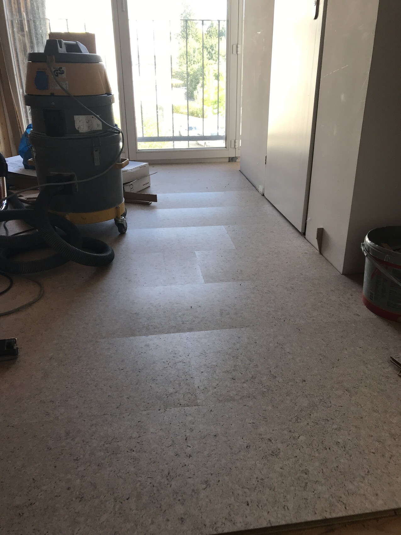 Raum mit Reinigungsgerät: Nass-Trockensauger, Kabel, Eimer, Tür zum Balkon.