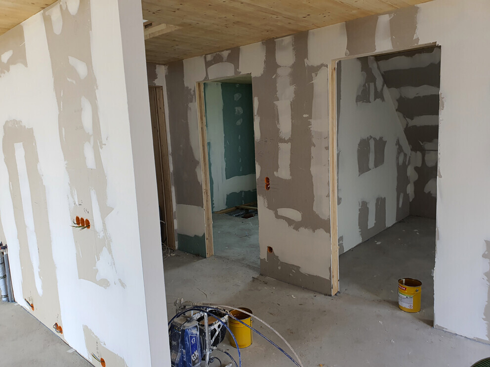 Innenansicht eines Bauprojekts mit verputzten Innenwänden und Baumaterialien im Innenausbau