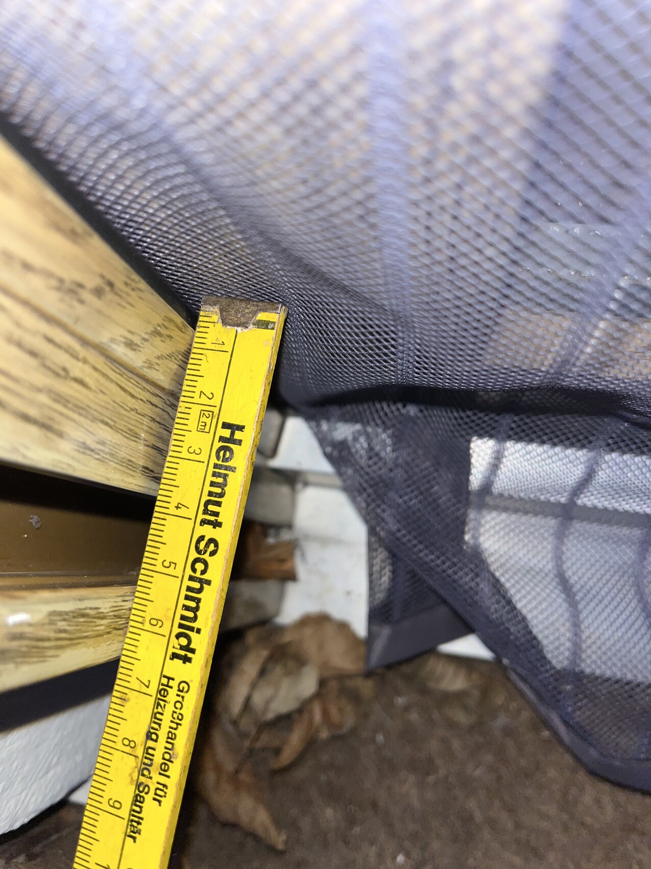 Nahaufnahme eines Maßbands im Baukontext, Holzrahmen und Netzgewebe sichtbar