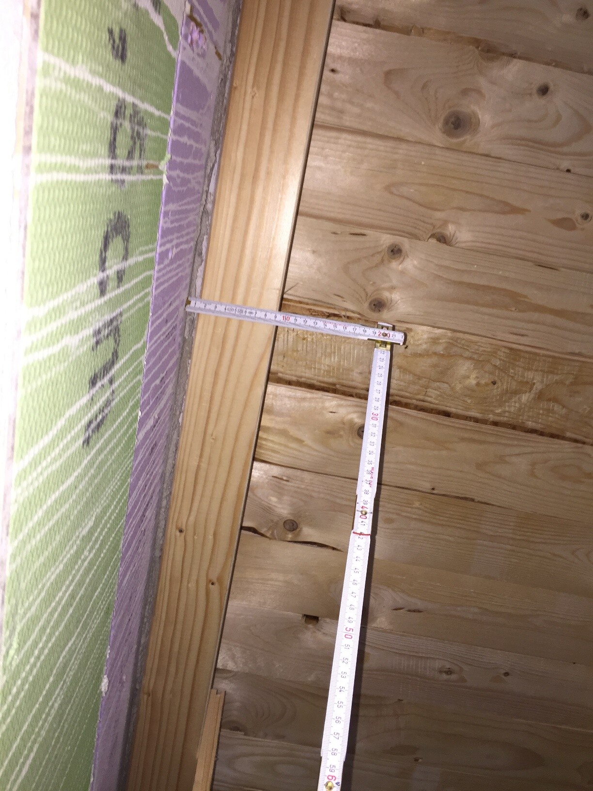 Innenausbau: Holzverkleidung, Dämmung und Maßband an der Wandseite.