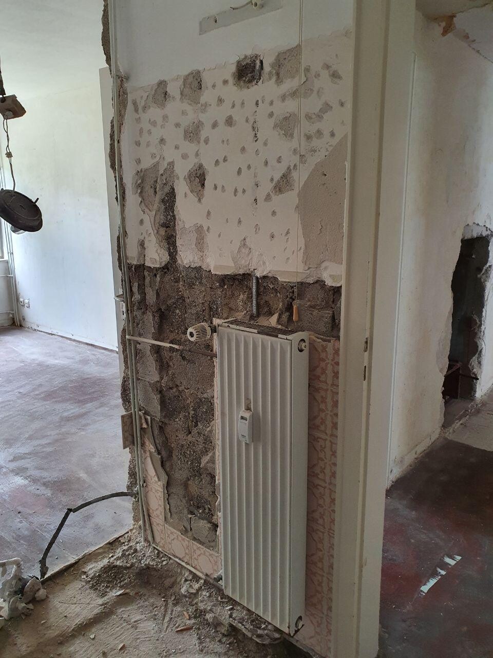 Renovierungsbereich mit Heizkörper, offener Wand und rohem Mauerwerk.