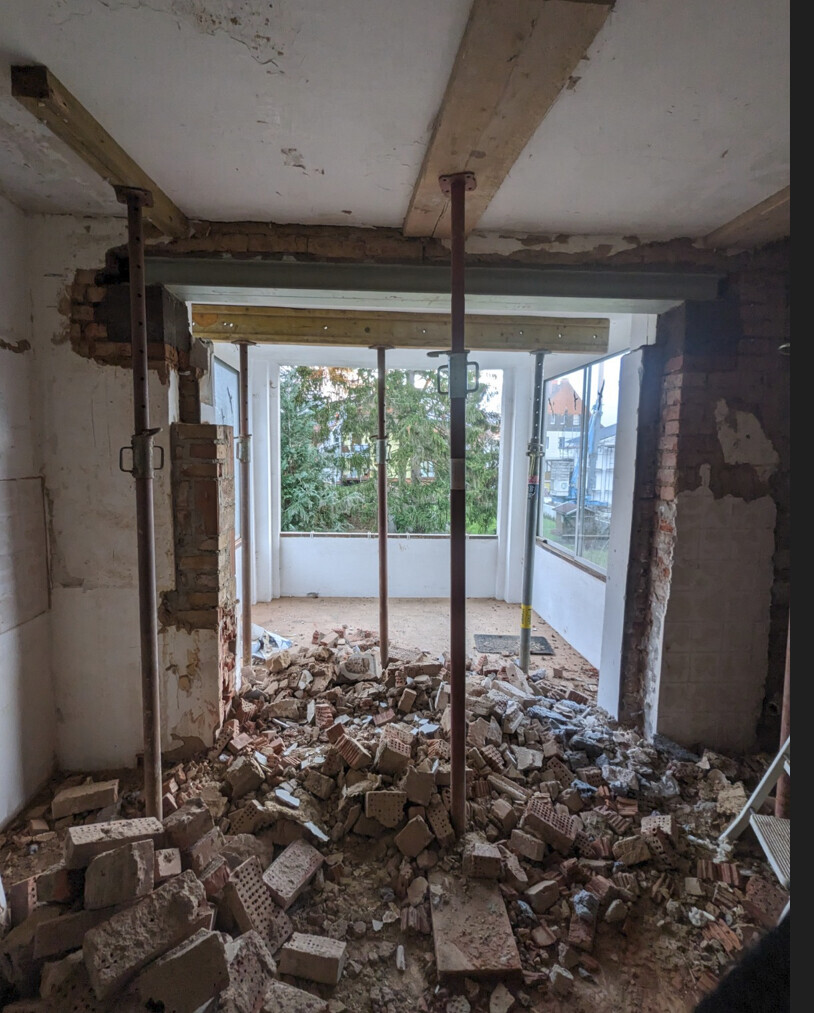 Innenraum Renovierung mit Bauschutt, Stützen und offener Fensterfront.