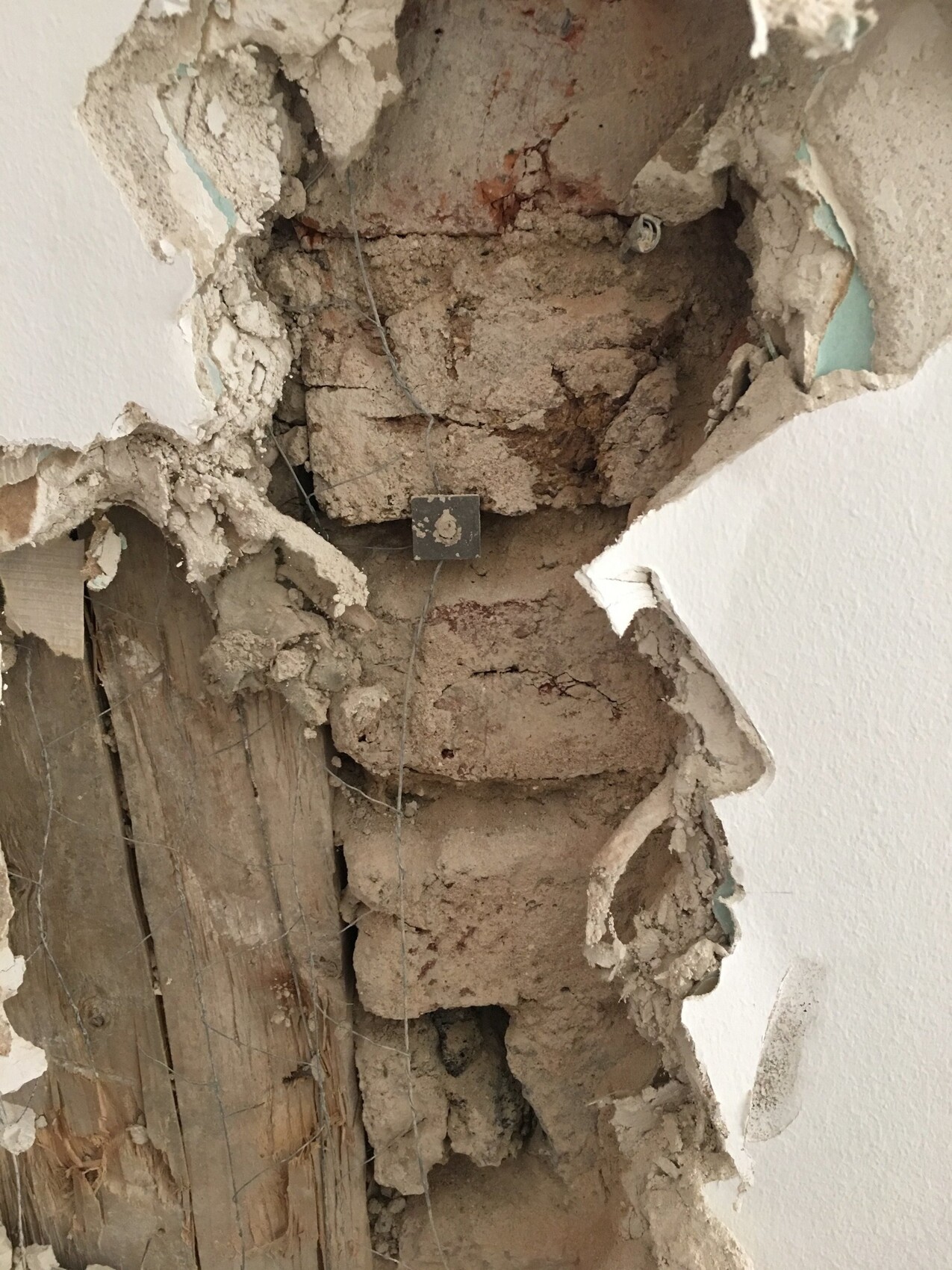 Freigelegte Wand mit Ziegeln, Rohbau und Kabel bei Innenrenovierung.