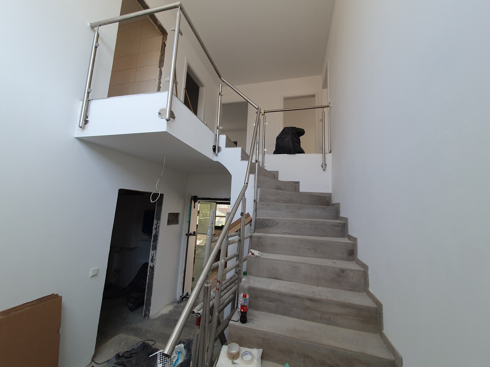 Innenansicht einer Treppe mit Edelstahlgeländer in hellem Innenraum während Renovierung.