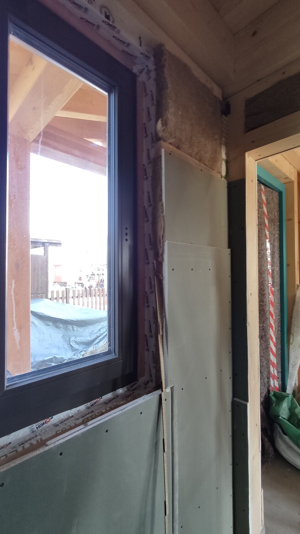 Innenraum einer Baustelle: Fensterrahmen, Dämmung, Gipsplatten an Holzständerwerk
