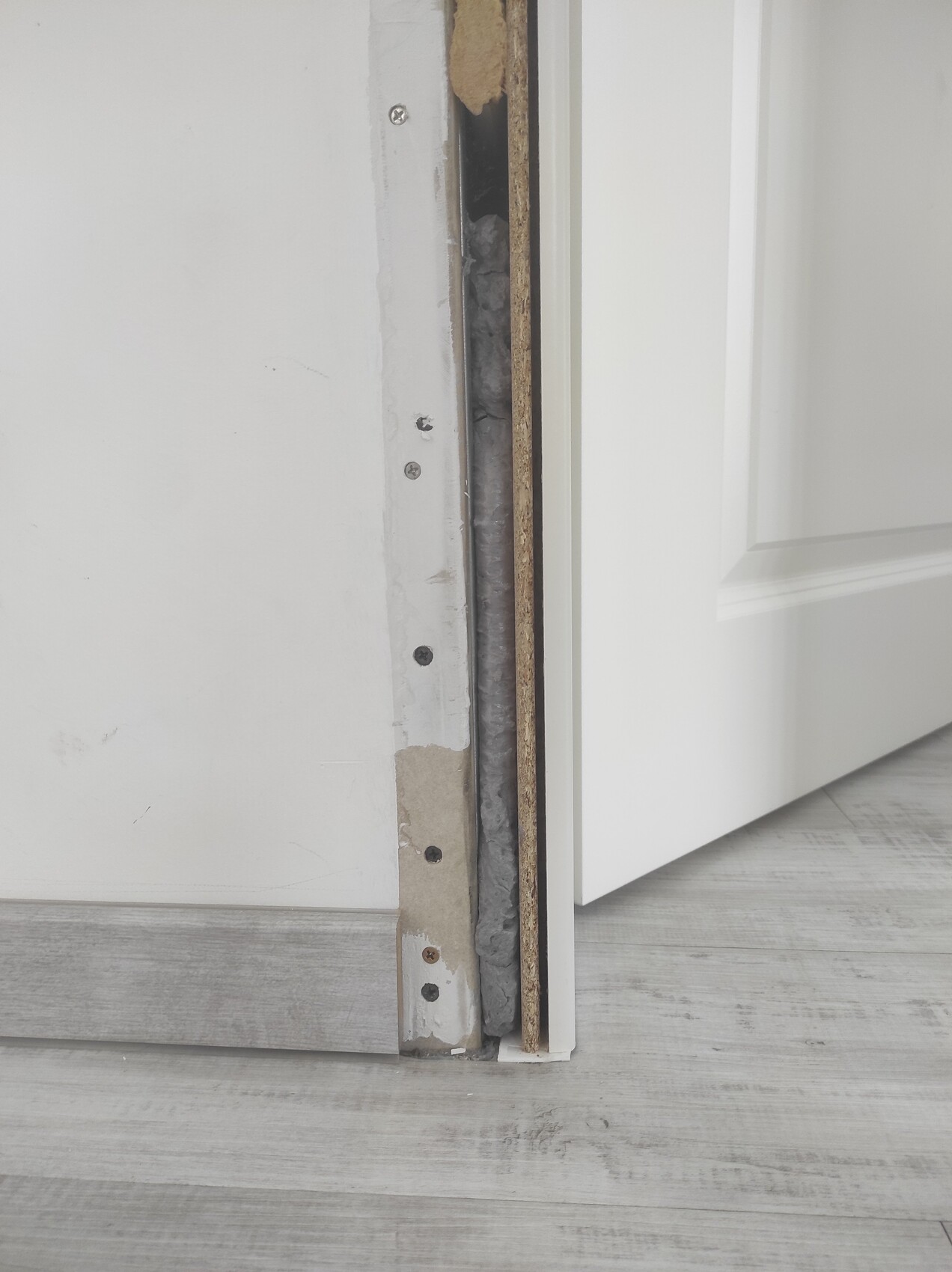 Türdurchgang im Renovierungszustand: offener Spalt, Dämmmaterial und Laminatboden sichtbar.
