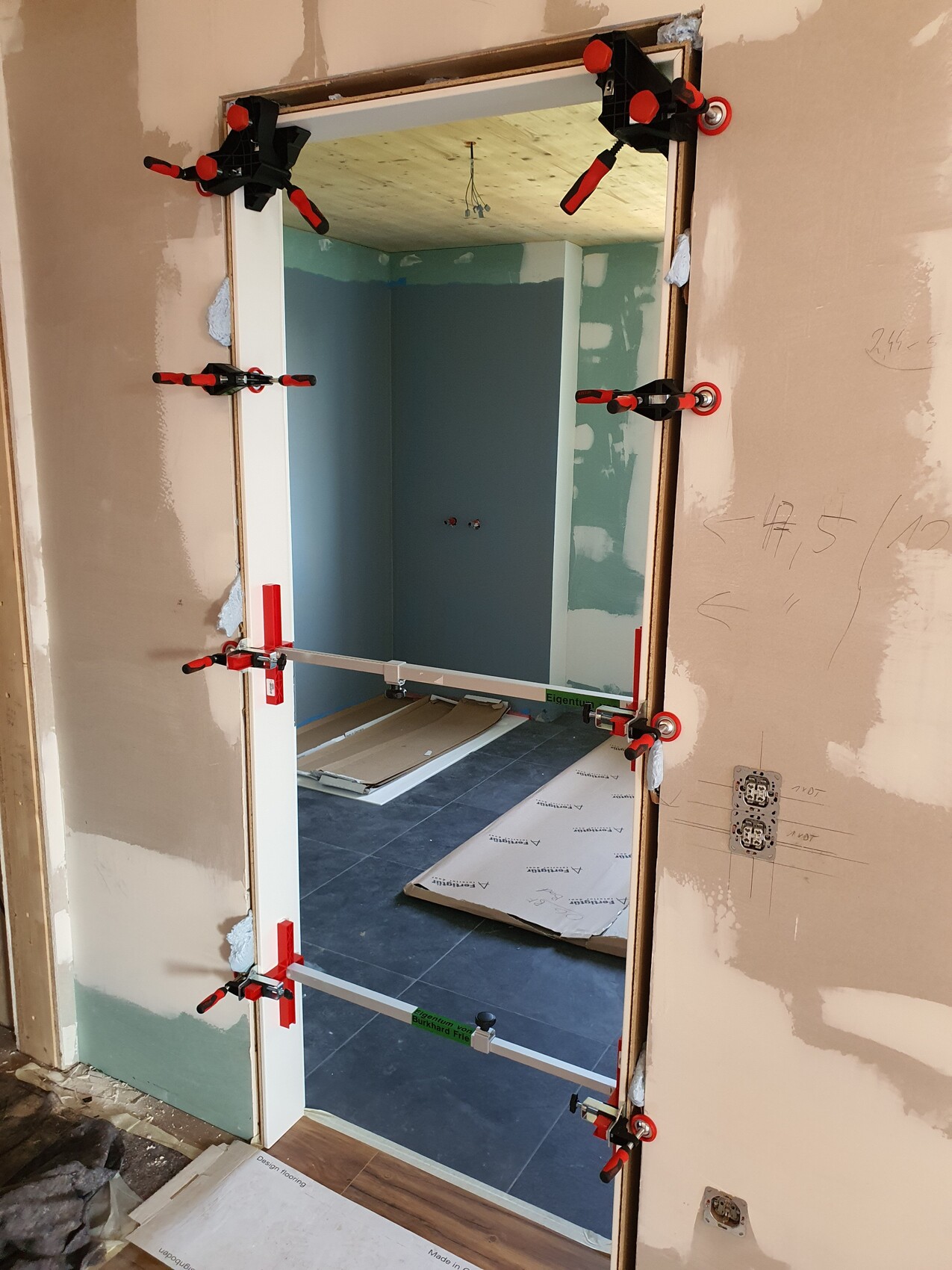 Türrahmen im Innenausbau wird mit Zwingen befestigt, Bauarbeiten im Nebenzimmer