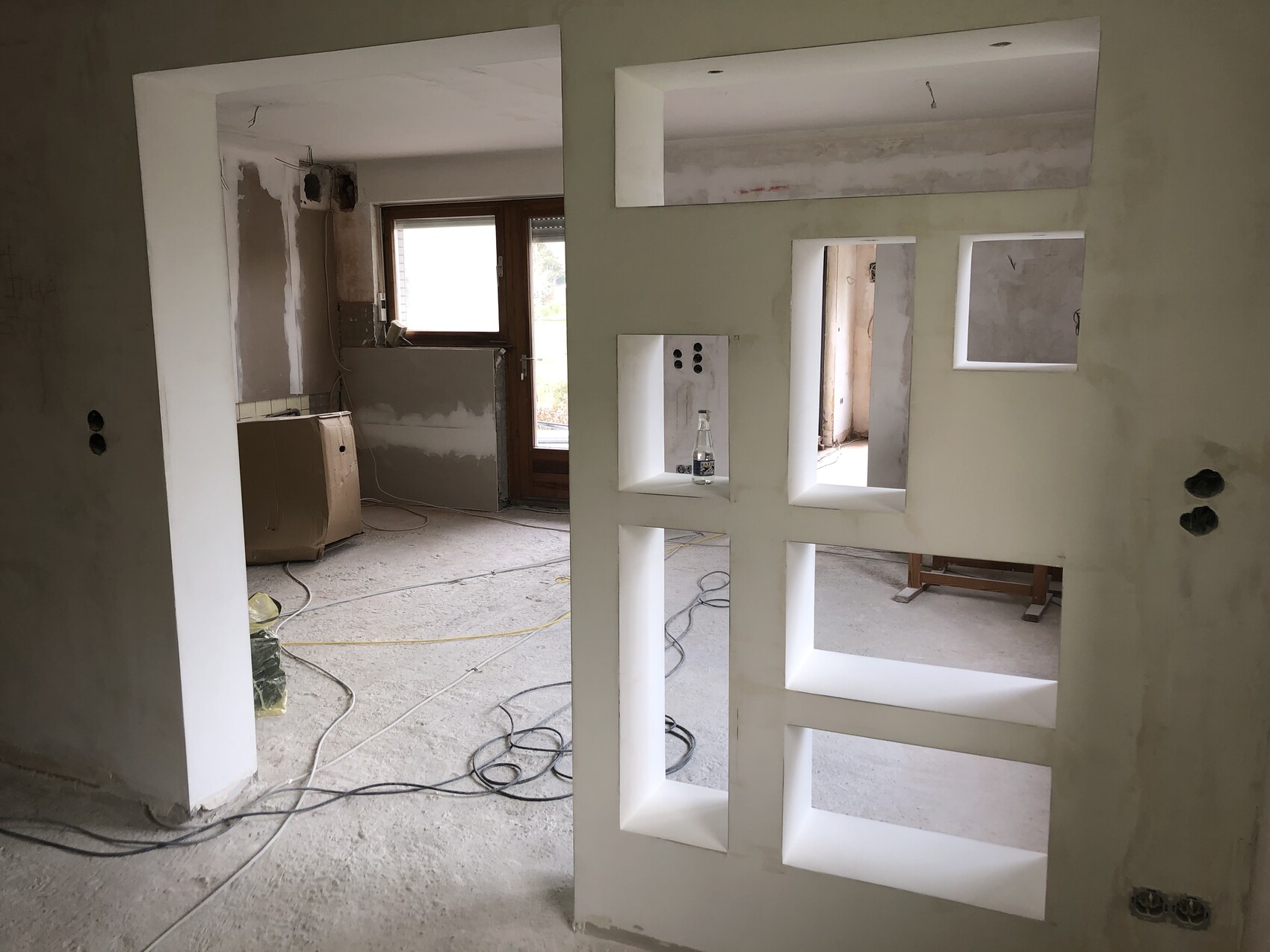 Innenausbau: Offener Innenraum mit Wandnischen, Kabeln und Baumaterialien im Bau