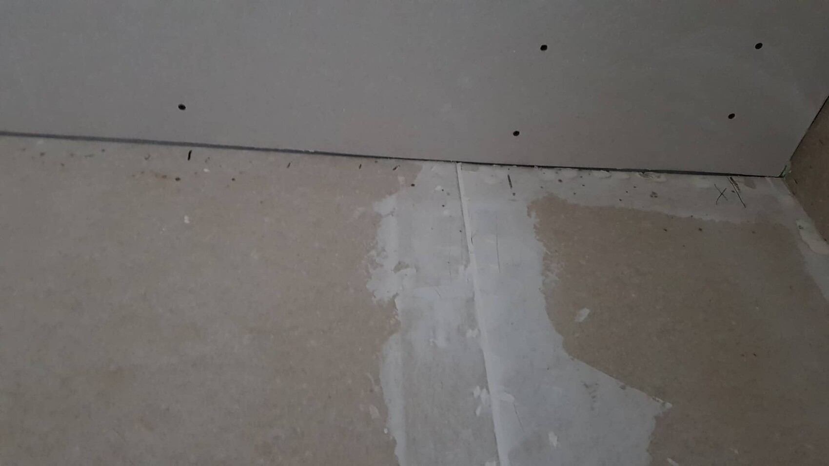 Rohbau Innenbereich mit rohem Betonboden und montierter Gipskartonwand