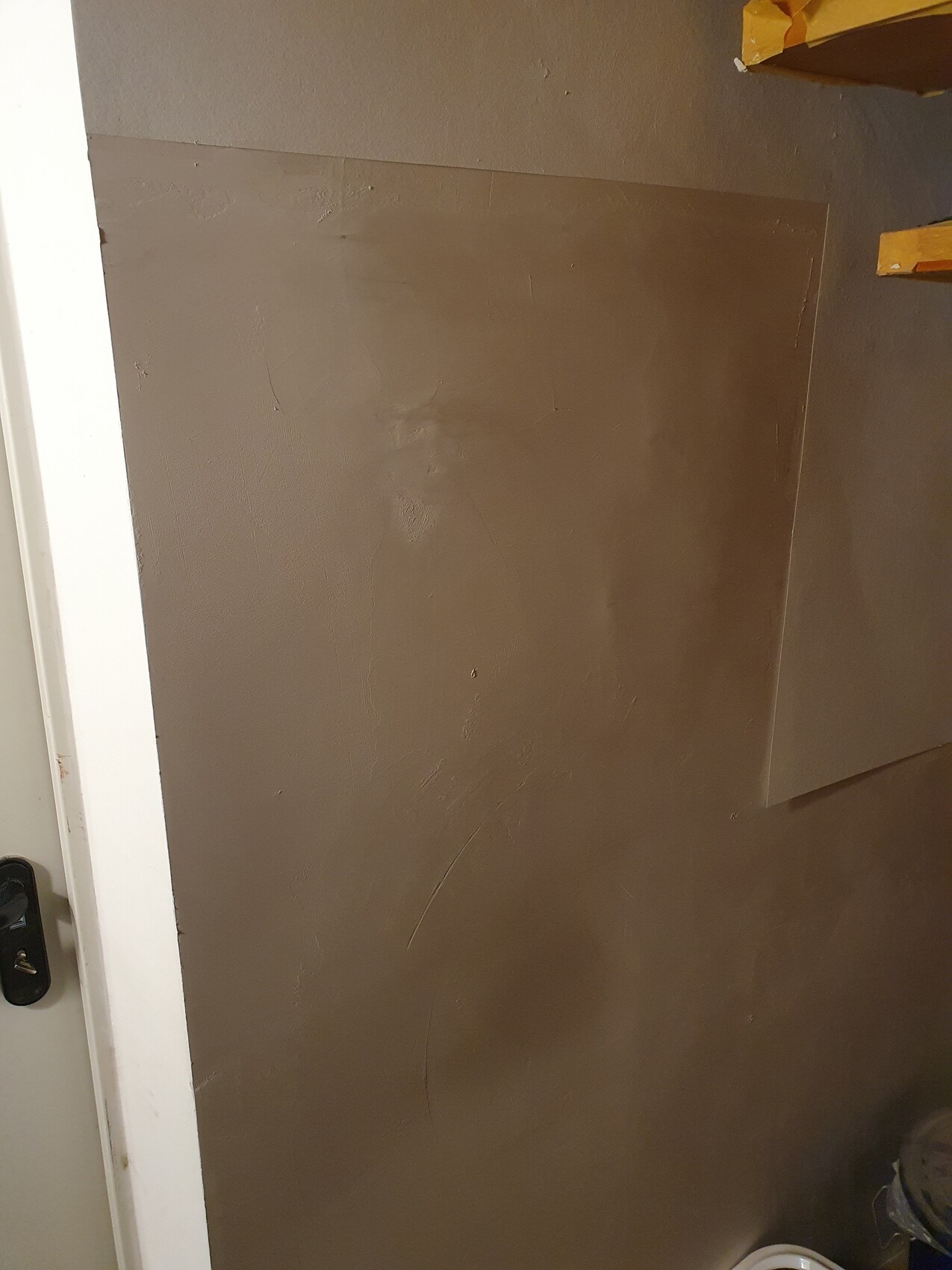 Innenwand mit braunem Putz, Spachtelspuren, Baustelle im Innenbereich.