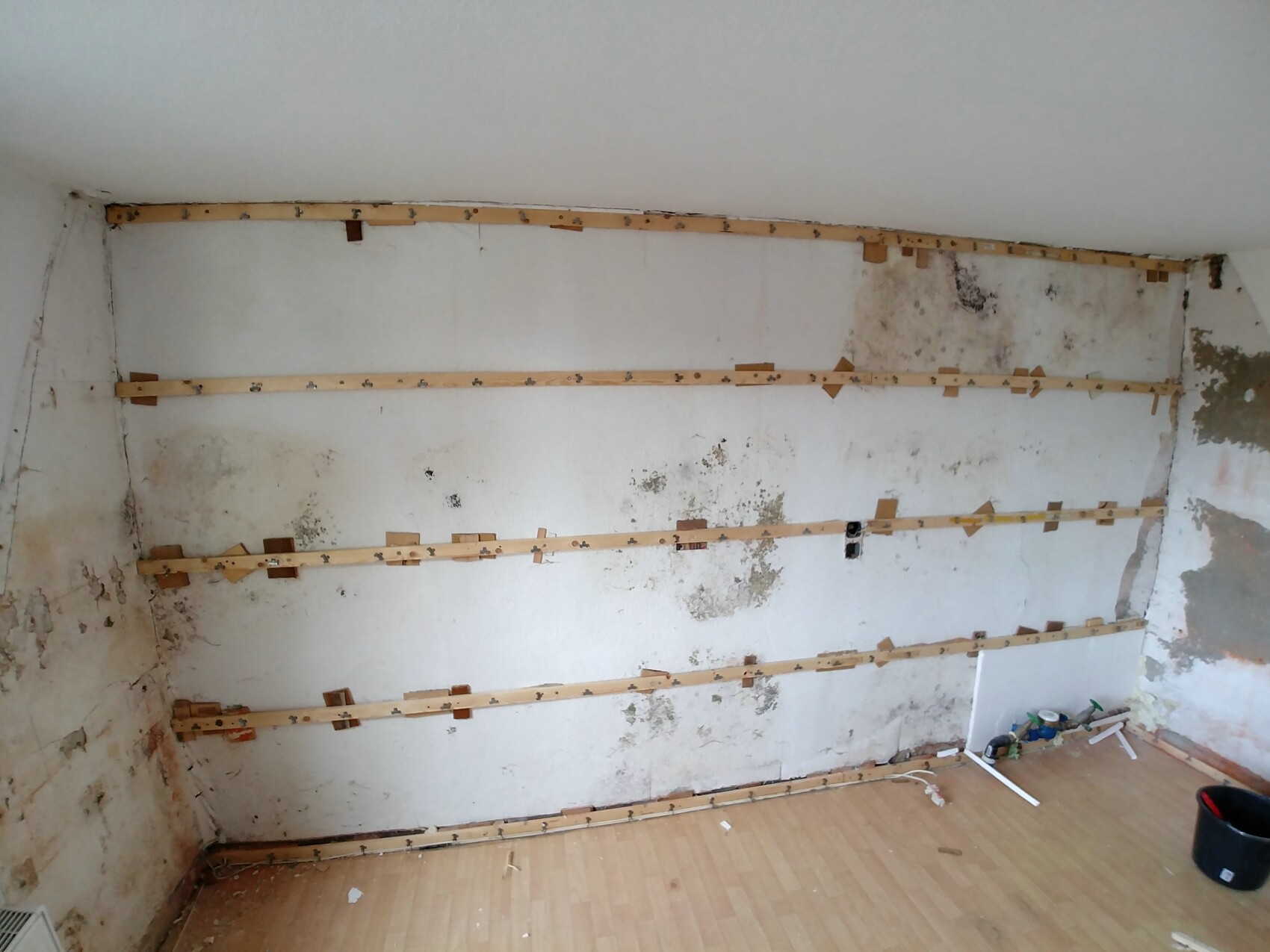 Raum im Innenausbau mit Wandlatten zur Verkleidung und Feuchtigkeitsschäden.