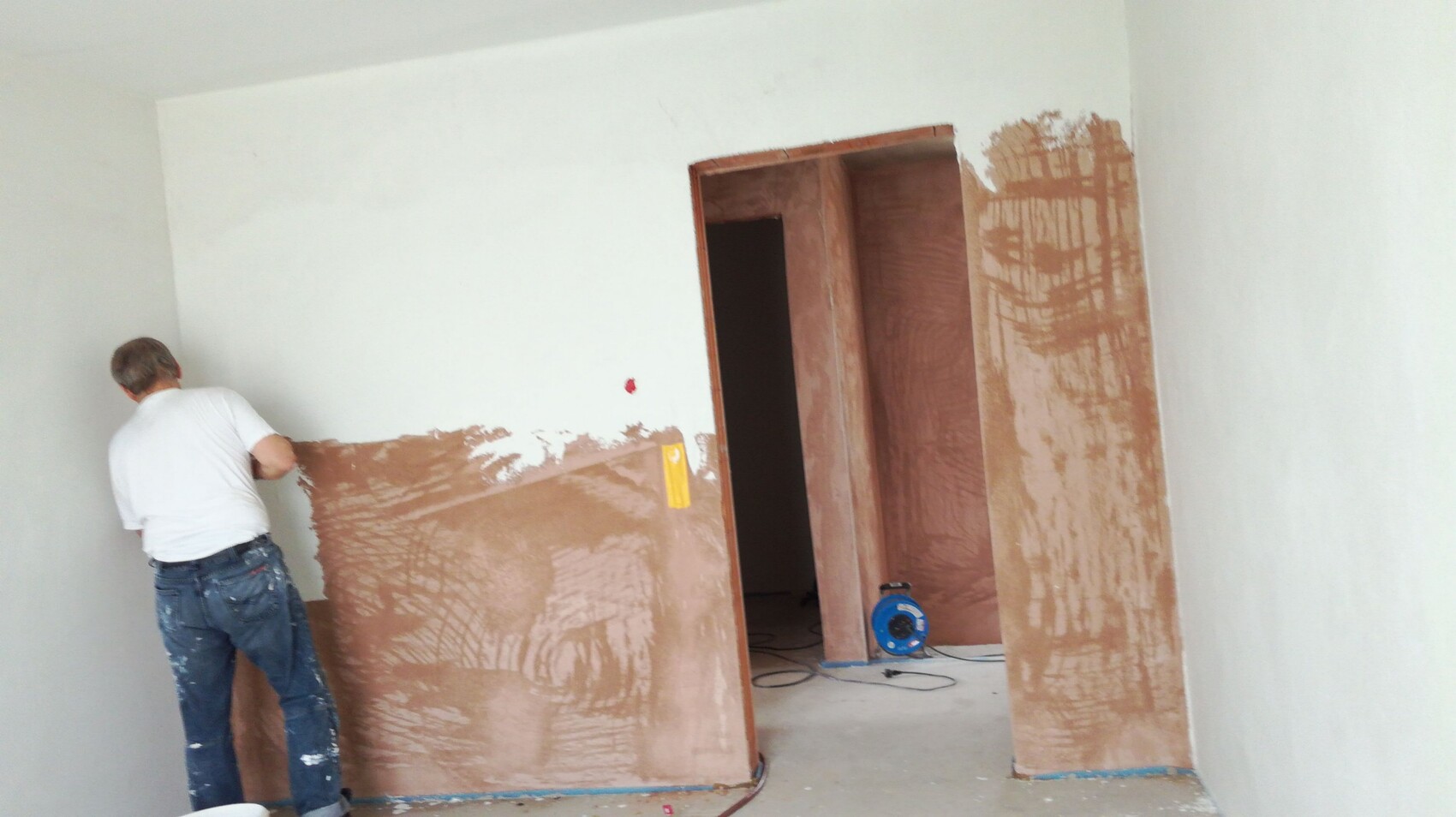 Mann verputzt Innenwand während Renovierungsarbeiten im Haus