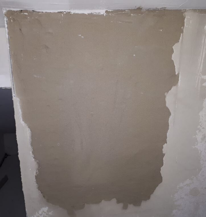 Innenwand mit frischem Putzbereich und ungleichmäßiger Oberfläche.