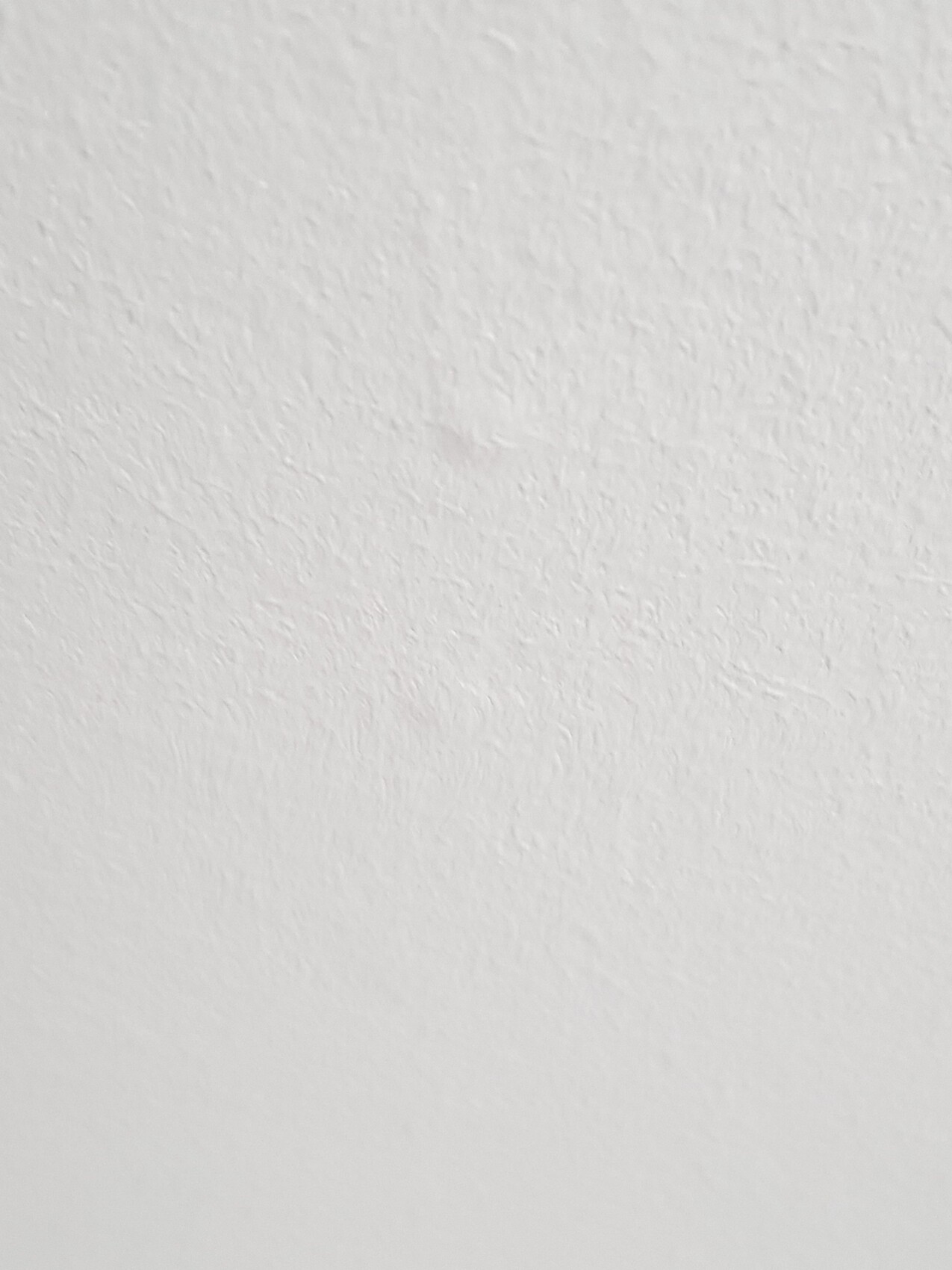 Weiße Wand mit leichter Struktur, kein Objekt ersichtlich.