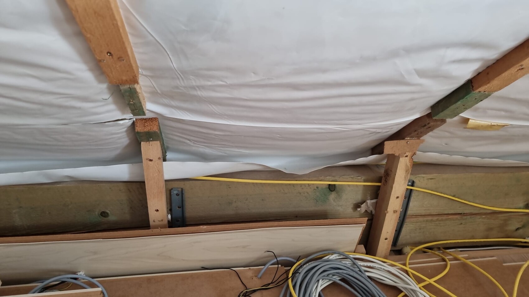 Baustelle im Innenbereich mit Holzbalken, Dämmfolie und losen Kabeln